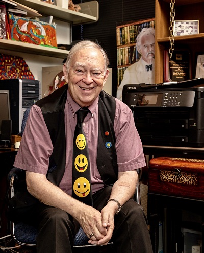 Geoffrey Grimes wearing a tie with smiley faces and sitting in his office.