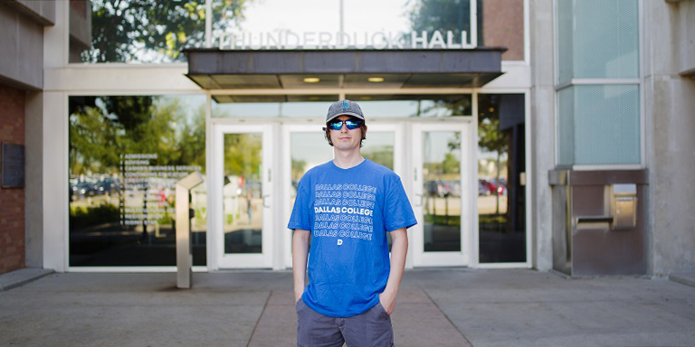 Jesse Serrano wearing Dallas College t-shirt and standing in front of Thunderduck Hall.