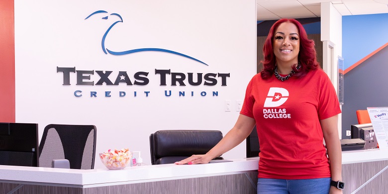 Krystal Hamilton standing in front of a Texas Trust Credit Union sign.