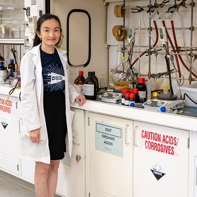 Dr. Mai Huynh in lab, wearing lab coat with Dallas College t-shirt underneath.