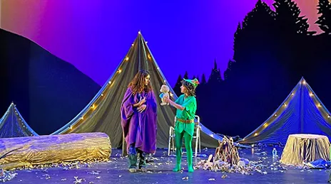 Actor presenting doll to other actor on stage.