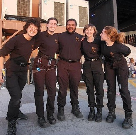 Stipe with the crew of the Santa Fe Opera, with all of them wearing black and smiling at the camera. A set is visible in the background.