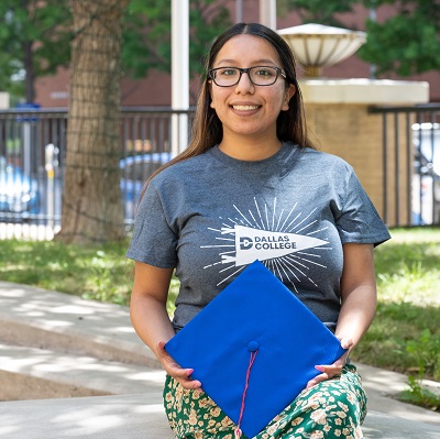 Daisy Donjuan standing outside holding her graduation cap.