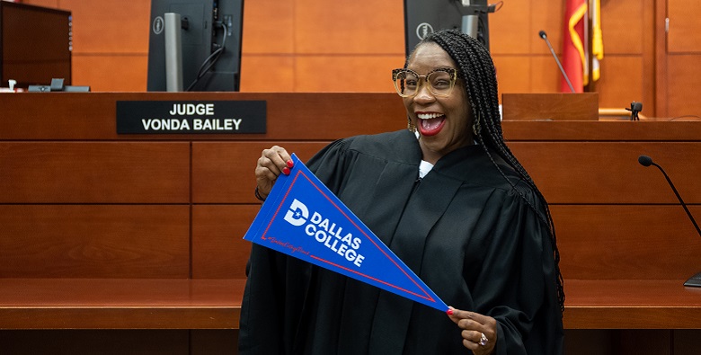 Judge Vonda Bailey holding Dallas College pennant.
