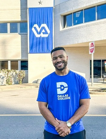 Dentist Davis wearing a blue Dallas College shirt while standing in front of a building.