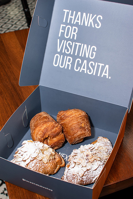 Display of packaging in La Casita Bakeshop with four croissants inside, with a blue box stating 