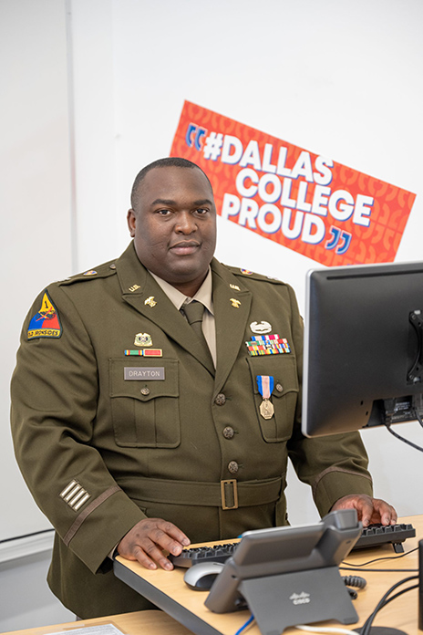 Army Captain Steven Drayton looking towards the camera while using a computer.