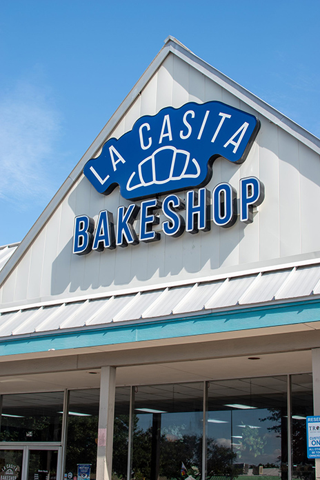 A photograph of La Casita Bakeshop outside in blue text with a croissant logo.