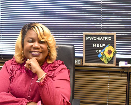 Nykesha, the Dallas College Counselor, sits at a desk in an office setting, with a letter board in the background that reads 