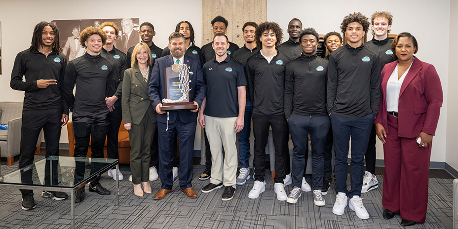North Lake championship basketball team poses with coach, athletic director, North Lake President Christa Slejko with Chancellor Justin Lonon holding trophy.
