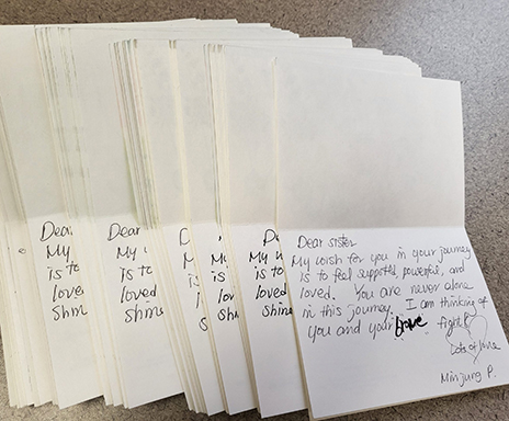 A close-up photo of several colorful handmade greeting cards filled with handwritten messages of encouragement and support, created by Dallas College ESOL students for breast cancer patients as part of a Breast Cancer Awareness Month outreach project.