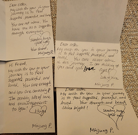A close-up photo of several colorful handmade greeting cards filled with handwritten messages of encouragement and support, created by Dallas College ESOL students for breast cancer patients as part of a Breast Cancer Awareness Month outreach project.
