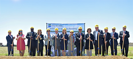 Line of people with shovels standing in front of a pile of dirt