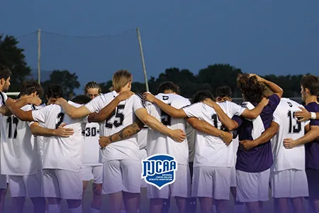 Group of soccer players huddle on the field.