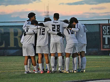 Richland men's soccer team in huddle on field.