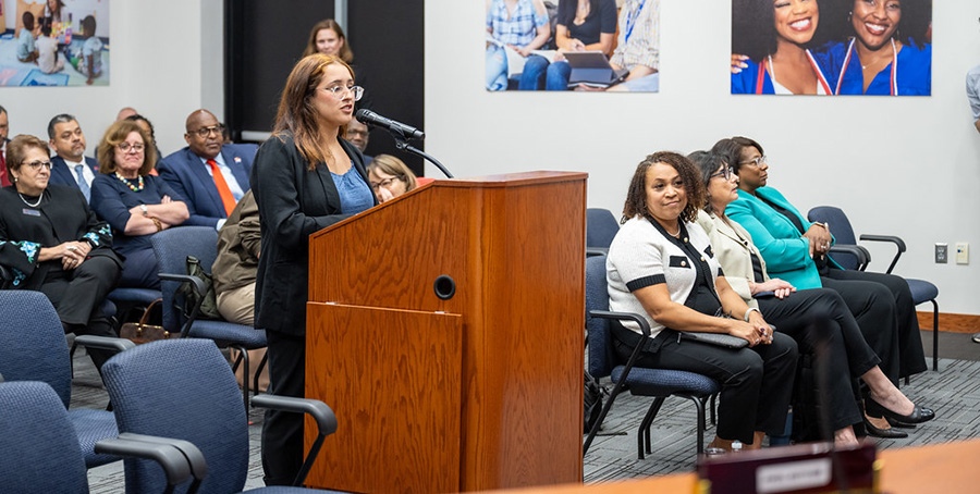 Malak behind podium addressing the board.