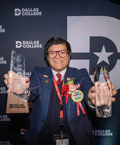 Kent Ho in front of Dallas College backdrop holding up awards.