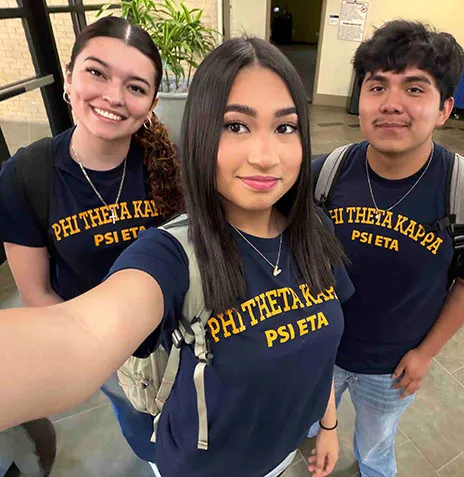 Three students in Phi Theta Kappa Psi Eta t-shirts pose for selfie.