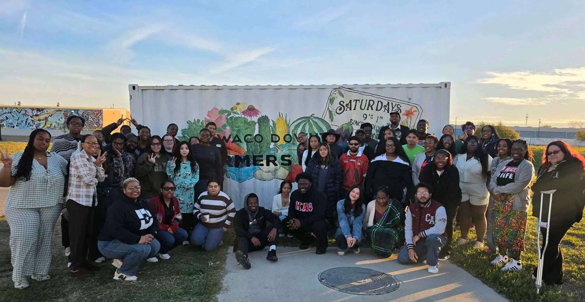 Group of students pose in front of a brick wall.