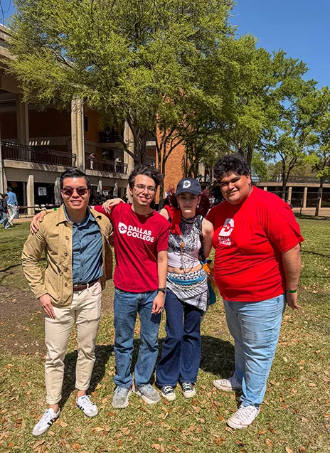 Four friends pose in front of campus building.