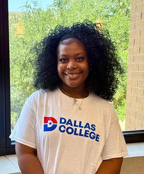 Student posing with Dallas College t-shirt.