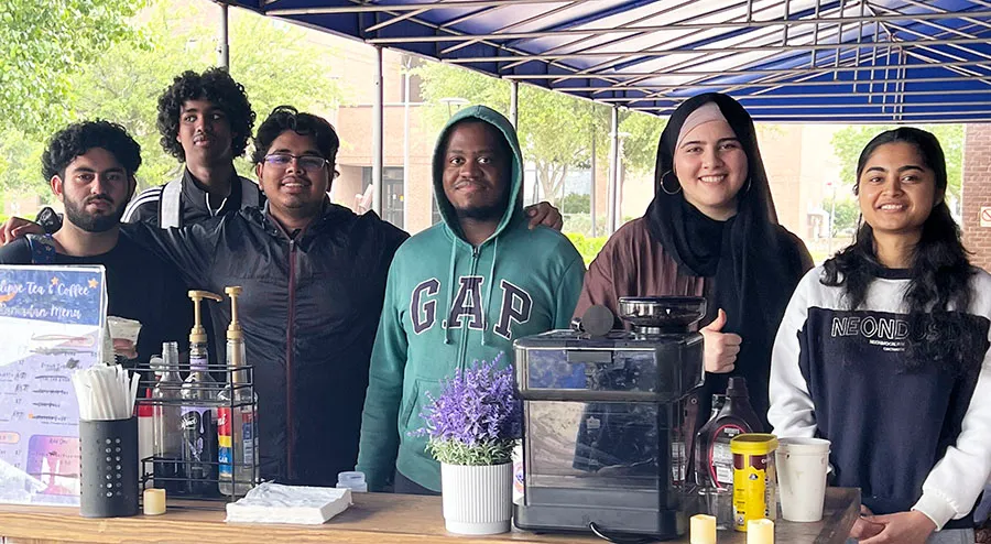 Group of students standing behind a table.