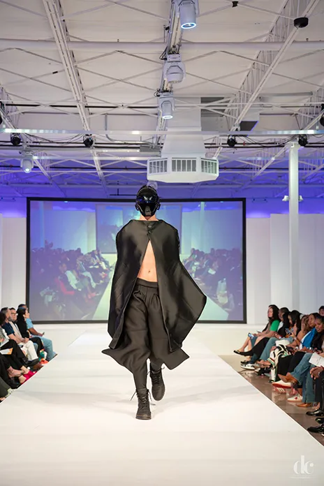 Male model wearing black garment on the runway.