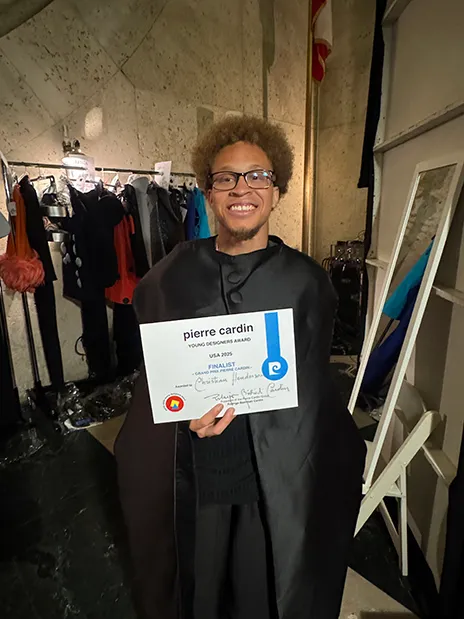 Christian Henderson holding Pierre Cardin finalist certificate.