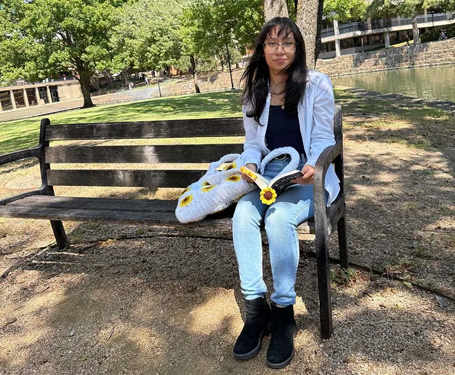 Evelyn Lainez sitting on bench reading book.