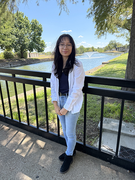 Evelyn Lainez standing on bridge with fountain in the background.