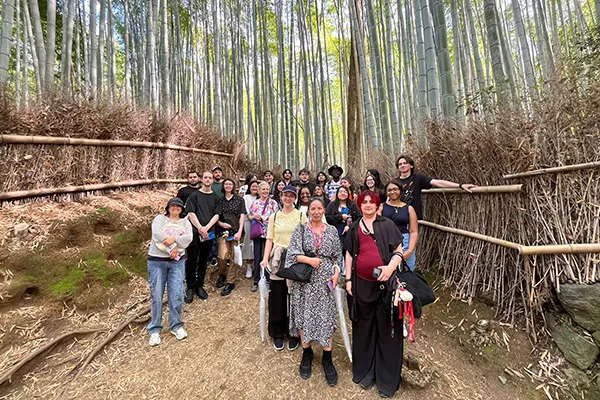 A group of Dallas College students stand surrounded by a bamboo forest in Japan.