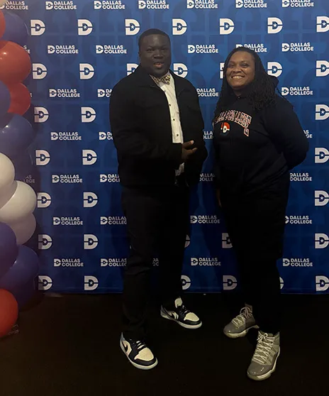 Larame Cunningham standing in front of step and repeat with administrator.