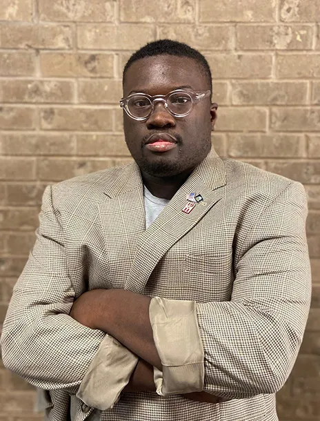 Larame Cunningham in suit jacket with arms crossed in front.