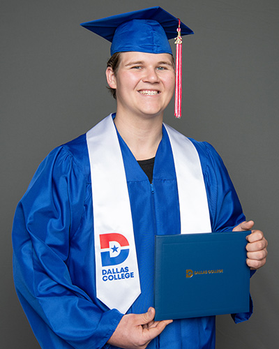 Michael Hovland is pictured wearing a cap and gown and holding a diploma