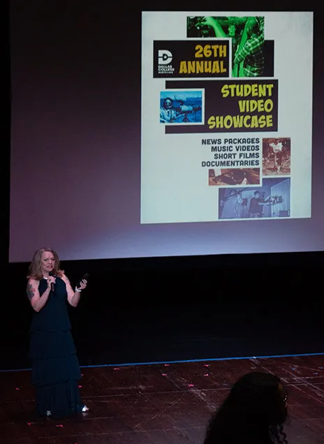 Sharie Vance with microphone in front of screen.