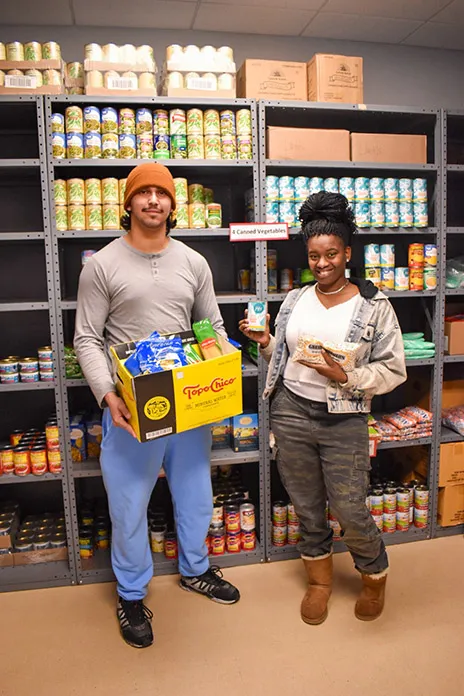 Two students holding groceries at food pantry.