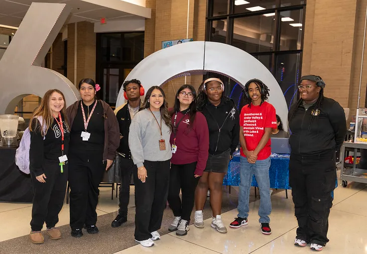 Group of students posing in front of 60th Anniversary sculpture.