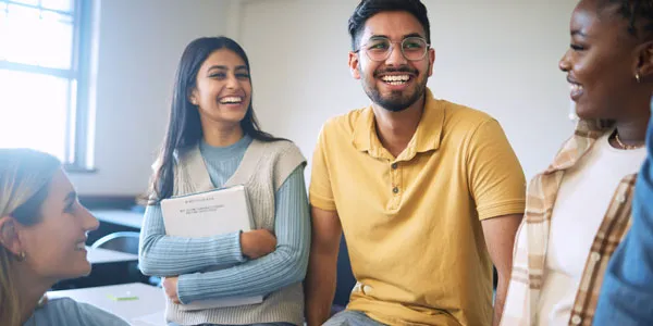 Students gathered together in class studying and smiling