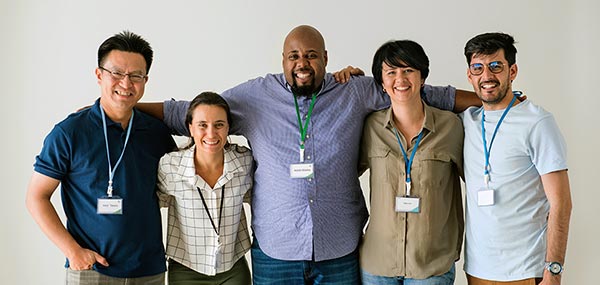 Group of five veterans standing together with arms around each other, wearing name tags and lanyards.