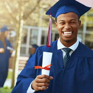 A student who graduated holding their diploma and smiling