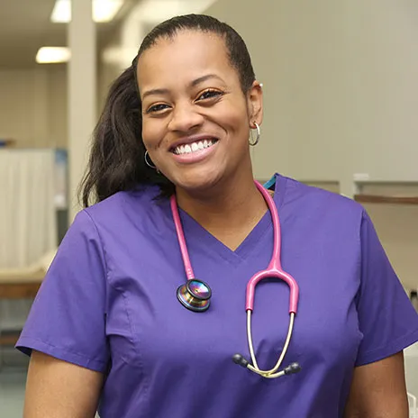 female nurse smiling in purple scrubs