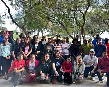 Student Ambassadors pose for a group photo under a large tree during their 2024 training