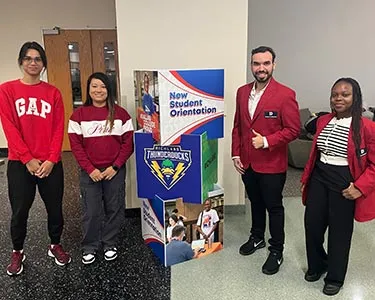 Student Ambassadors stand near signage for NSO at Richland