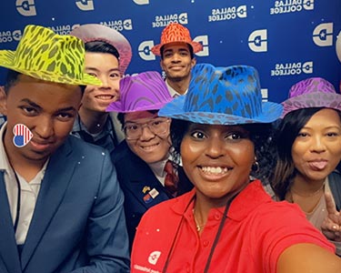 Student Ambassadors wear a variety of hats and pose for a photo in front of a Dallas College backdrop