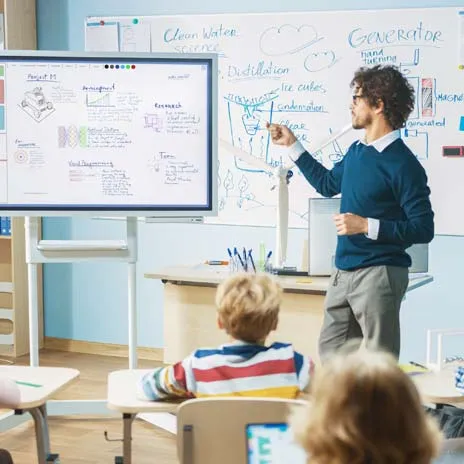 A teacher points to a presentation on a digital screen