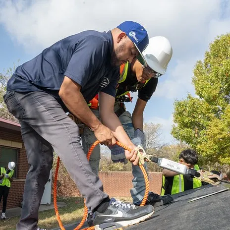 A student and instructor work on a roof to practice safety measures
